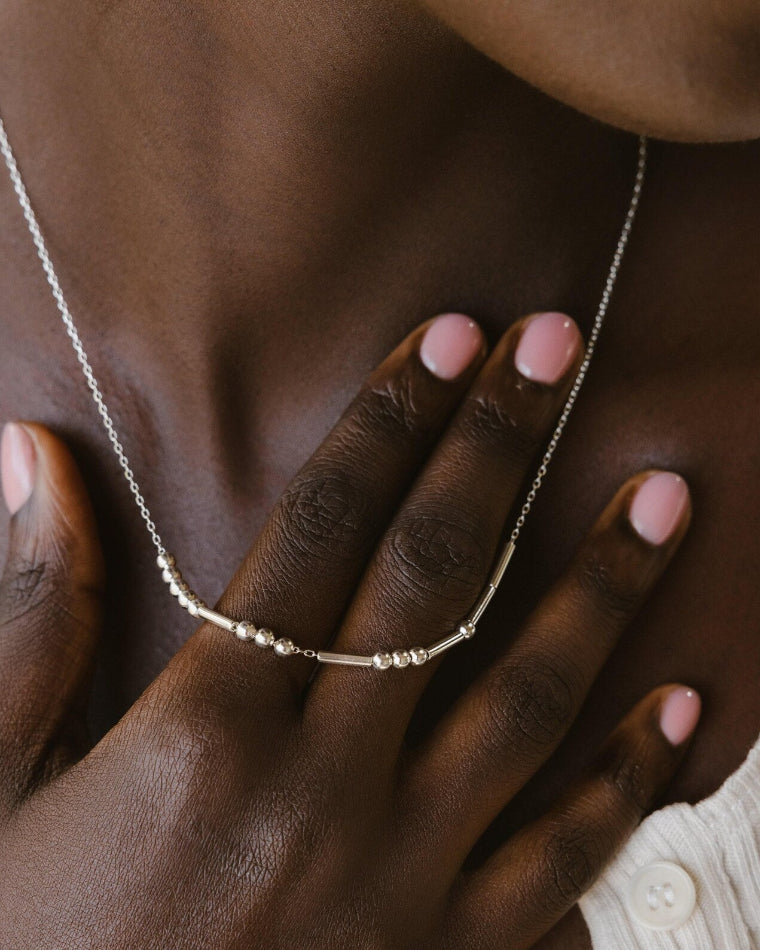 Necklace being worn by a person with hands on a textured surface